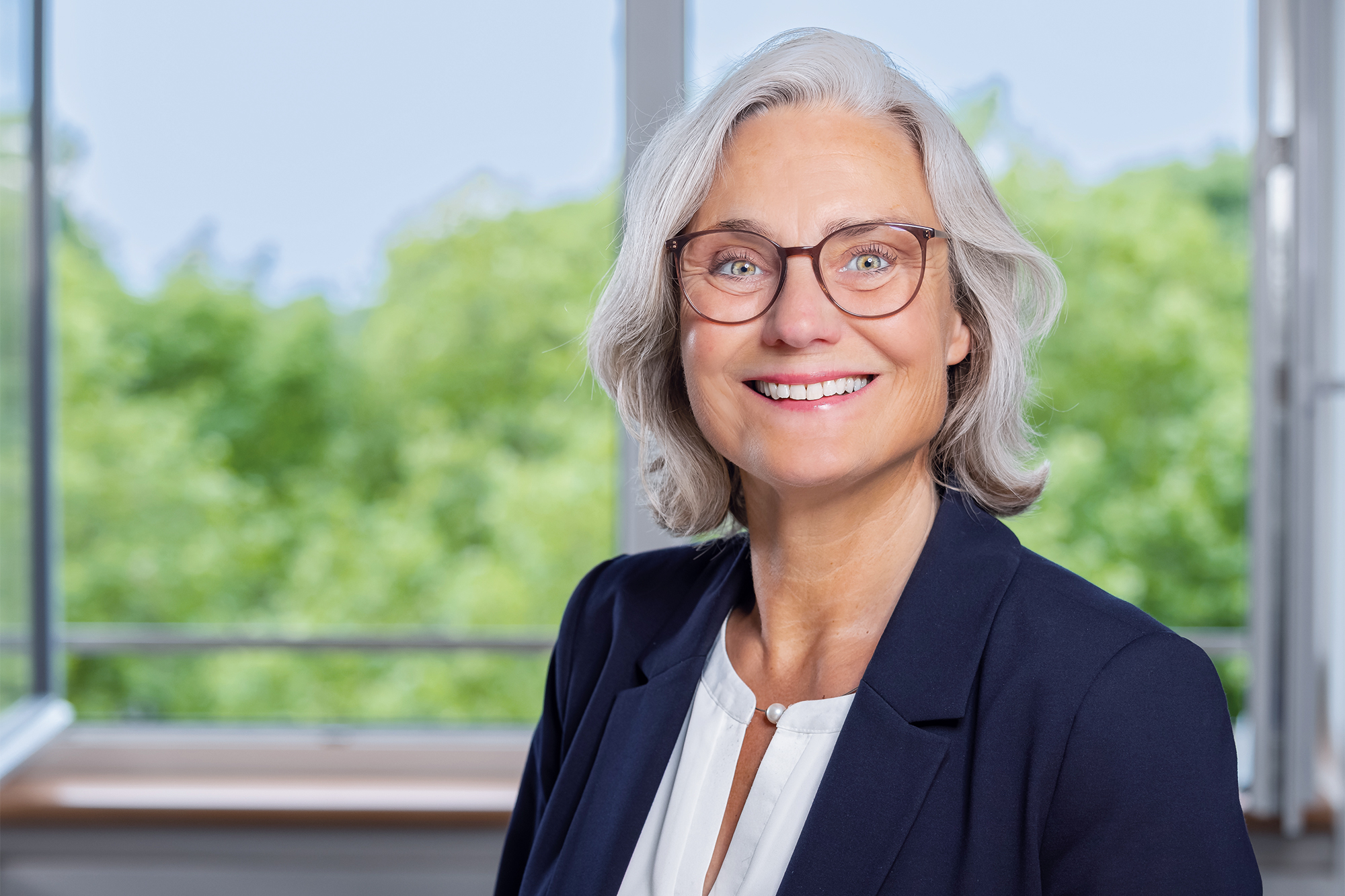Eine Frau mit kinnlangem Haar, schwarzem Blazer und Brille lächelt in die Kamera. (c) Annette Schrader Eine Frau mit kinnlangem Haar, schwarzem Blazer und Brille lächelt in die Kamera.